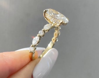 May include: A gold engagement ring with a large oval-shaped diamond center stone and smaller diamonds set in a pave setting along the band.
