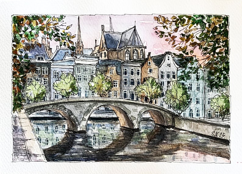 May include: Watercolor painting of a bridge over a canal in a European city. The bridge is made of stone and has three arches. There are buildings on both sides of the canal, and trees lining the banks. The sky is a soft pink and blue.