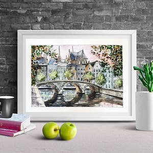 May include: Watercolor painting of a bridge over a canal in a European city. The buildings are in the background and have a light brown color. The bridge is made of stone and has a light gray color. The water is a light blue color. The painting is framed in a white frame.