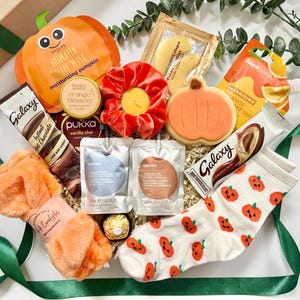 May include: A gift box containing a pumpkin-shaped sheet mask, a red velvet scrunchie, a pumpkin-shaped cookie, a pair of white socks with orange pumpkin patterns, a fuzzy orange headband, Galaxy hot chocolate, Pukka tea, and skincare pouches.