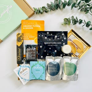 May include: A gift box filled with self-care items, including face masks, bath products, tea, and chocolate. The box is decorated with a green label that says "White Eucalyptus".