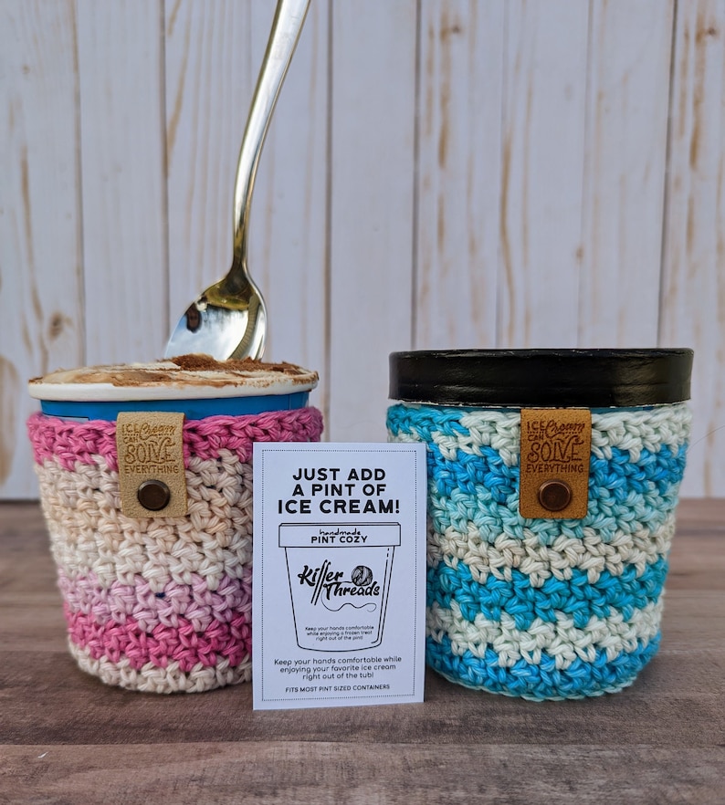 K&ouml;nnte beinhalten: Zwei geh&auml;kelte Becher-Cozies in rosa und blauen Streifen. Die Cozies sind so konzipiert, dass sie in Pint-gro&szlig;e Beh&auml;lter passen. Der Text auf der Karte lautet "Just add a pint of ice cream! Handmade Pint Cozy Killer Threads Keep your hands comfortable while enjoying your favourite ice cream right out of the tub. Fits most pint-sized containers."
