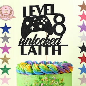 May include: Black glitter cake topper with a video game controller, the number 8, and the text "Level 8 unlocked Laith".