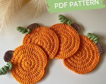 May include: Four crocheted pumpkin coasters in orange with green stems. The coasters are arranged in a circle with the stems facing outwards.  PDF PATTERN.