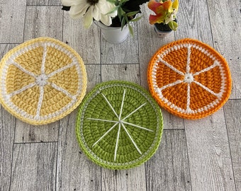 Puede incluir: Tres posavasos de ganchillo en forma de limón, lima y naranja. Los posavasos están hechos con hilo amarillo, verde y naranja y tienen un contorno blanco.