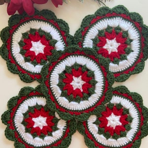 Peut inclure: Ensemble de cinq dessous-de-verre en crochet de couleur verte, blanche et rouge avec un motif de poinsettia.