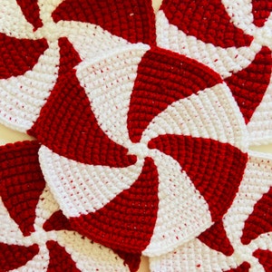 Peut inclure: Gros plan sur quatre ornements en crochet en forme de spirale de menthe poivr&eacute;e rouge et blanche. Les ornements sont faits avec un motif en spirale et sont parfaits pour un projet d'artisanat de vacances.