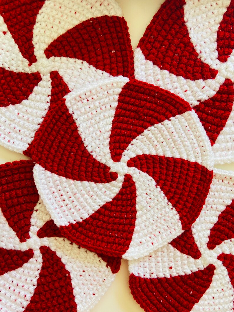 Peut inclure: Gros plan sur quatre ornements en crochet en forme de spirale de menthe poivr&eacute;e rouge et blanche. Les ornements sont faits avec un motif en spirale et sont parfaits pour un projet d'artisanat de vacances.