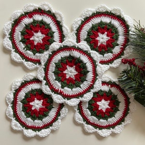 Peut inclure: Ensemble de cinq dessous-de-verre en crochet rouge, blanc et vert avec un motif en &eacute;toile.
