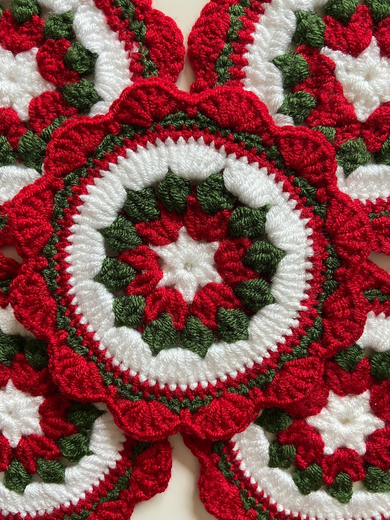 Peut inclure: Quatre dessous-de-verre en crochet de couleur rouge, blanche et verte. Les dessous-de-verre sont circulaires et pr&eacute;sentent un motif floral r&eacute;p&eacute;titif.