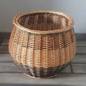Peut inclure: Un grand panier rond en osier avec un motif tissé brun et naturel. Le panier est fait de matériaux naturels et a un aspect rustique.