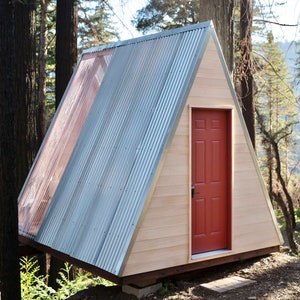 Pu&ograve; includere: Una piccola capanna di legno triangolare con una porta rossa e un tetto di metallo. La capanna &egrave; circondata da alberi.