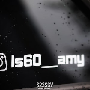 以下が含まれることがあります： 黒い表面に白いInstagramのロゴと「ls60_amy」の文字。下に「S23SGV PHOTOGRAPHY」の文字。表面には水滴が付着しています。