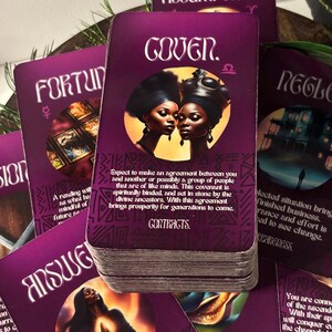 Op de afbeelding: Een set tarotkaarten met paarse en gouden accenten. De kaarten bevatten illustraties van mensen en symbolen. De kaart op de voorgrond toont twee vrouwen met een donkere huidskleur en een gouden kroon. De tekst op de kaart luidt "Gover. &Omega;".