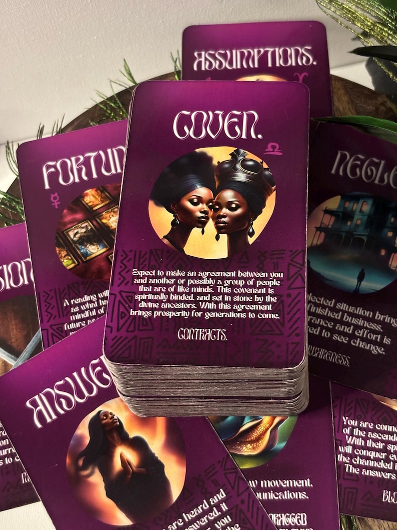 Op de afbeelding: Een set tarotkaarten met paarse en gouden accenten. De kaarten bevatten illustraties van mensen en symbolen. De kaart op de voorgrond toont twee vrouwen met een donkere huidskleur en een gouden kroon. De tekst op de kaart luidt "Gover. &Omega;".