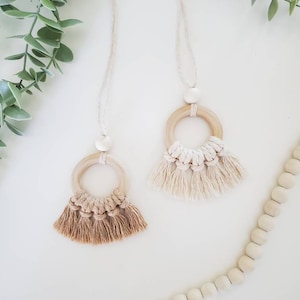 May include: Two wooden circle necklaces with tassels. The necklaces are made of natural wood and have a simple, minimalist design. The tassels are made of a soft, natural fiber and are available in two colors: beige and brown.