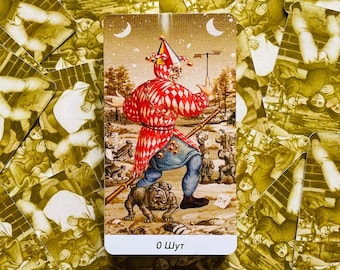 Op de afbeelding: Een tarotkaart met een kleurrijke illustratie van een nar die een staf vasthoudt. De kaart is getiteld "0 Nar".
