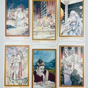 May include: Tarot card deck featuring illustrations of the Major Arcana cards. The cards are in a gold frame with a white background. The cards are arranged in three rows of three cards each. The cards are numbered from I to XXI.