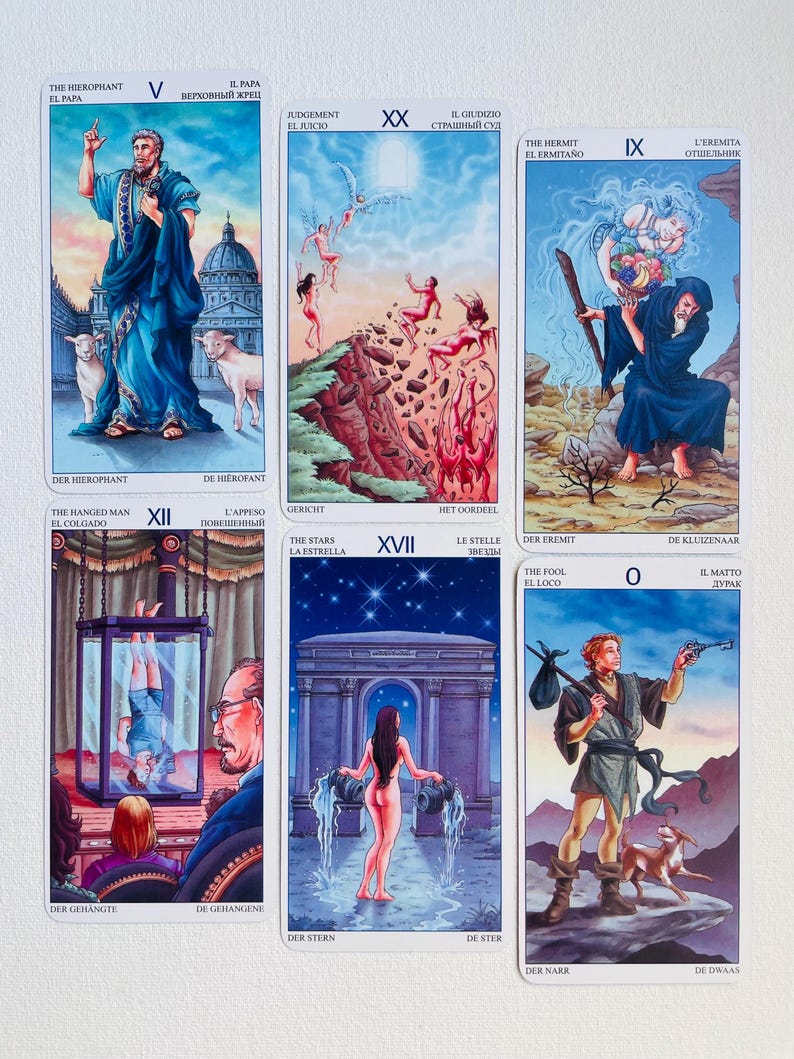 May include: A set of 22 tarot cards with colorful illustrations and text in multiple languages. The cards are arranged in a grid of 5 columns and 4 rows. The cards feature a variety of characters and scenes, including a man in a blue robe, a woman with a crown, a man hanging from a tree, and a woman standing in a doorway.