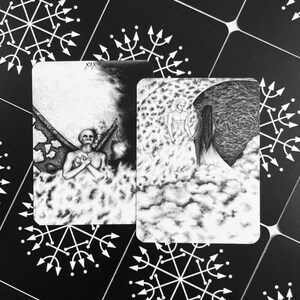 Może przedstawiać: Dwie czarno-białe karty tarota na białym tle. Karta po lewej stronie ma numer XIX i szkieletową postać ze skrzydłami. Karta po prawej stronie przedstawia postać z aureolą i postać z długimi włosami.