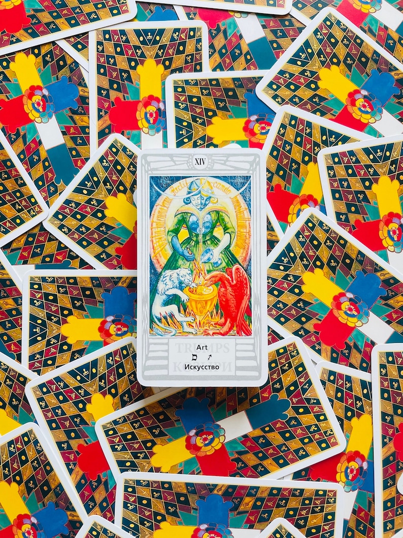 Pu&ograve; includere: Una carta dei tarocchi con sfondo bianco e bordo argentato. La carta &egrave; numerata XIV e la parola "Art" &egrave; scritta al centro della carta. La carta rappresenta una donna con un vestito verde che tiene un piccione bianco e un uccello rosso. La donna &egrave; circondata da un cerchio di luce.