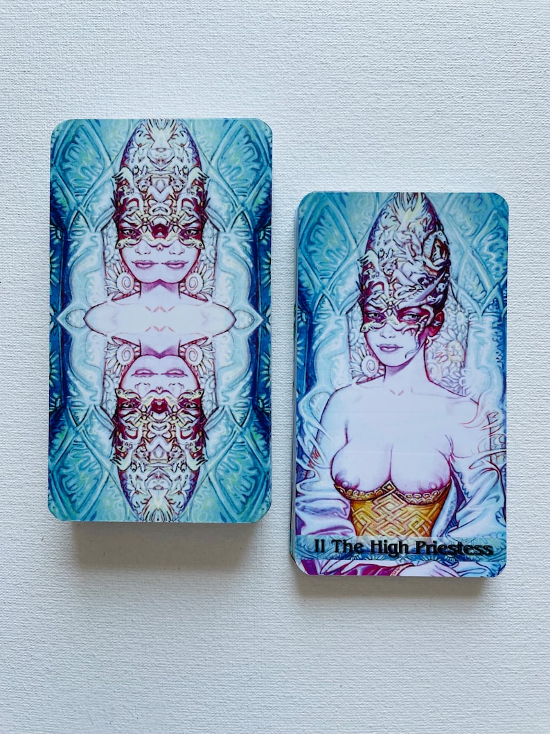 K&ouml;nnte beinhalten: Zwei Tarotkarten, eine mit blauem Hintergrund und einer Frau mit Maske und die andere mit rosa Hintergrund und einer Frau mit Maske und dem Text "II Die Hohepriesterin".