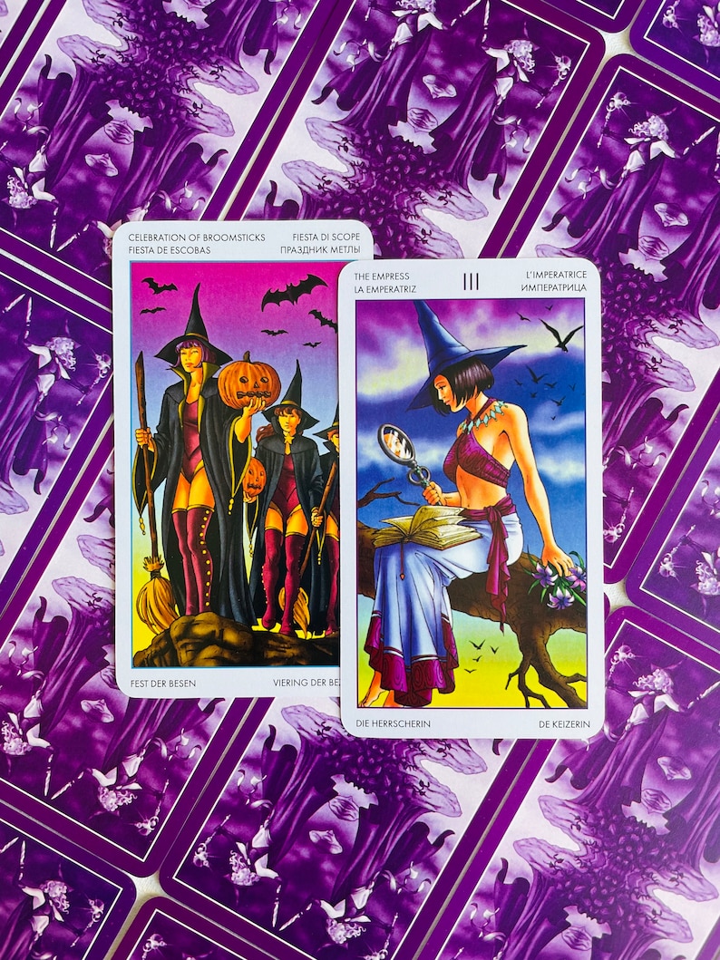 Peut inclure: Deux cartes de tarot, l'une repr&eacute;sentant trois sorci&egrave;res avec des balais et des citrouilles, et l'autre montrant une femme en robe bleue assise sur une branche avec un livre et un miroir. Les cartes sont des jeux "L'Imp&eacute;ratrice" et "C&eacute;l&eacute;bration des balais".