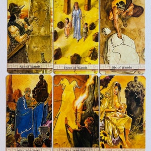 May include: A set of ten tarot cards featuring illustrations of people and scenes from the suit of Wands. The cards are in a yellow and brown color scheme with gold accents. The cards are arranged in two rows of five cards. The cards are labeled with the names of the cards: Ace of Wands, Three of Wands, Six of Wands, Nine of Wands, Ten of Wands, Queen of Wands.