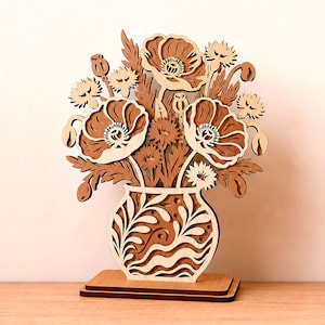 May include: A laser-cut wooden floral arrangement featuring layered poppies and wildflowers in a decorative vase with wavy patterns. The piece stands on a rectangular base and includes labels for 1/8 inch, 3 mm, and 4 mm thickness, plus a Digital Download tag.