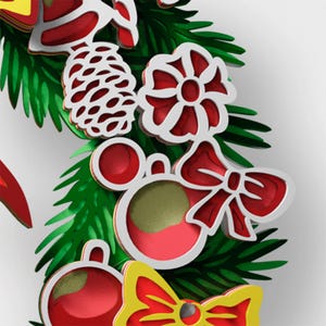 May include: A layered Christmas wreath decoration featuring green pine needles, a white pinecone, a red flower, a red bow, and red circular ornaments with gold accents. The design uses stacked cutouts to create depth with vibrant red, green, and yellow.