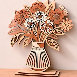 May include: A layered wooden cutout of a bouquet of flowers in a vase, featuring various shades of light and dark wood. The design includes multiple daisy-like blooms and leaves. Text labels indicate 1/8 in, 3 mm, 4 mm, and Digital Download.