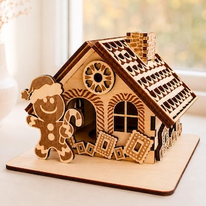 Puede incluir: Una casa de jengibre de madera cortada con láser que incluye un personaje sonriente con un bastón de caramelo, una chimenea y adornos de galletas. La estructura muestra etiquetas de 1/8 in, 3 mm, 4 mm y Digital Download.