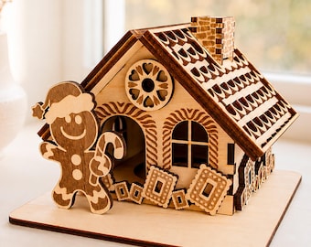 May include: A laser-cut wooden gingerbread house model featuring a smiling gingerbread person holding a candy cane, a chimney, and decorative cookie accents. The structure includes text labels for 1/8 in, 3 mm, 4 mm, and Digital Download.