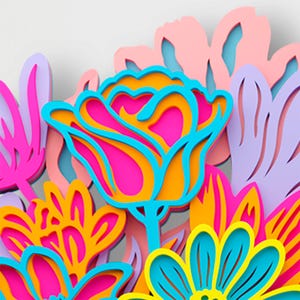 May include: A multi-layered wall art piece featuring stylized flowers in vibrant shades of hot pink, bright orange, turquoise blue, sunny yellow, and soft lavender. The design uses stacked cutouts to create depth, with bold outlines and shapes.