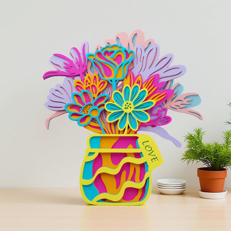May include: A multi-layered wooden cutout of a bouquet of flowers in a vase. The flowers are in shades of pink, purple, blue, and yellow. The vase is blue, yellow, and pink with a yellow tag attached to the side that has the word LOVE printed on it.