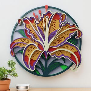 May include: A layered paper art piece featuring a stylized lily flower. The flower has yellow, red, and purple petals with a white center, set against a dark green circular background. Green leaves and red stamens add detail.