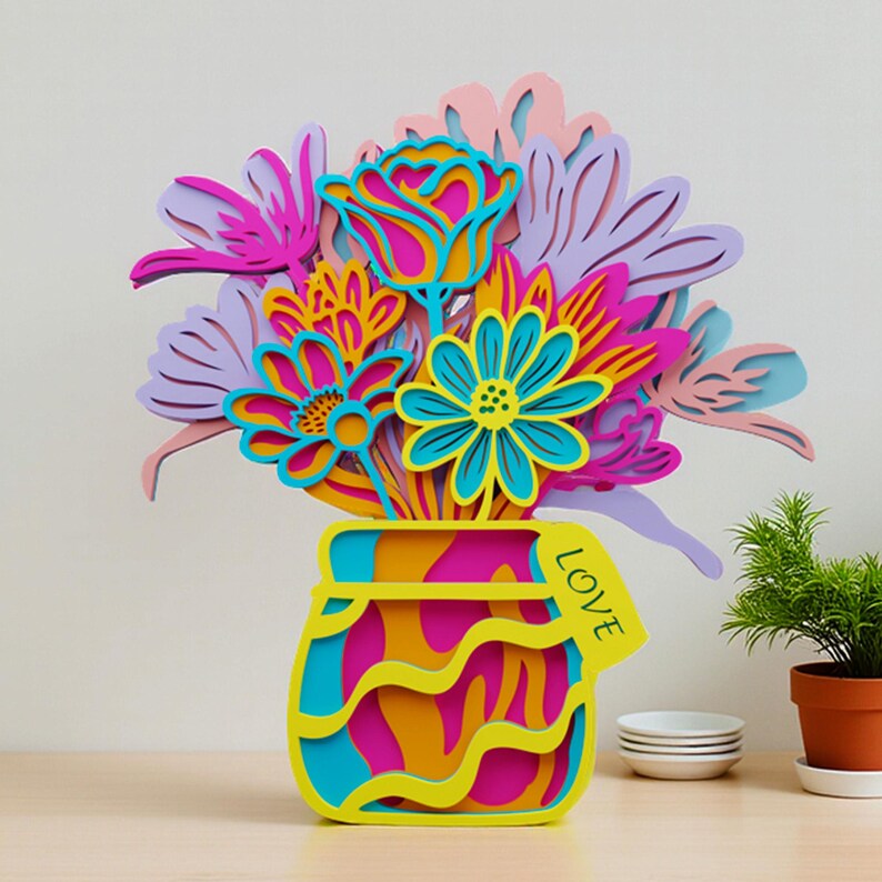 May include: A multi-layered wooden cutout of a bouquet of flowers in a jar. The flowers are in shades of pink, purple, yellow, and blue. The jar is yellow, pink, and blue with the word LOVE printed on a small tag attached to the side.