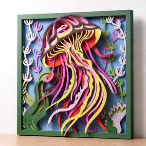 Peut inclure: Une œuvre d'art murale tridimensionnelle multicouche représentant une méduse dans des tons de violet, rose, jaune et orange. La méduse est entourée de plantes aquatiques stylisées blanches, vertes et lavande, le tout dans un cadre vert foncé.