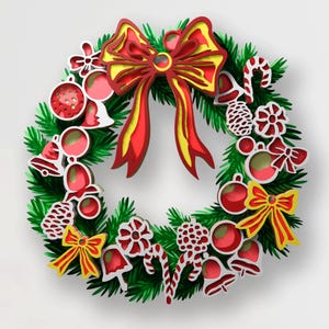 May include: A layered paper-cut style Christmas wreath featuring a large red and yellow bow at the top. The wreath is decorated with red and white ornaments, bells, candy canes, pinecones, and smaller bows against a green pine needle base.