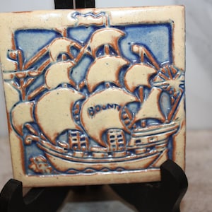 May include: A white ceramic mug with a black handle and the text "But First, Coffee" in a bold, black font. The mug is set against a blurred background, suggesting a cozy setting.