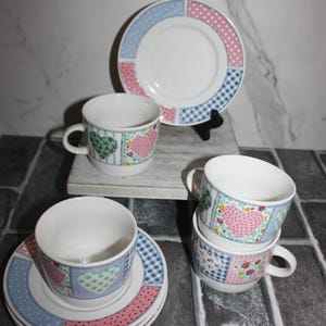 May include: A charming tea set featuring cups, saucers, and plates with a patchwork design. The set includes a plate and cups with heart and floral patterns in pink, blue, and green. The set is made of ceramic.