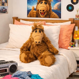 May include: A brown plush toy resembling the character ALF, featuring shaggy fur, a large snout, and dark eyes, sitting on a white bedspread. The plush has tan paw pads and a tuft of hair on its head, mirroring the ALF poster displayed on the wall.