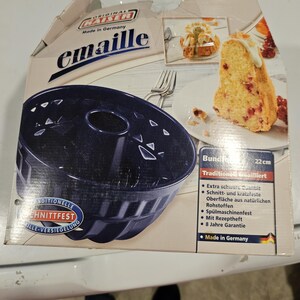 May include: A dark blue bundt cake pan in its original packaging. The box features the brand name "Kaiser emaille" and a picture of a slice of cake. The pan is 22 cm in diameter and made in Germany.