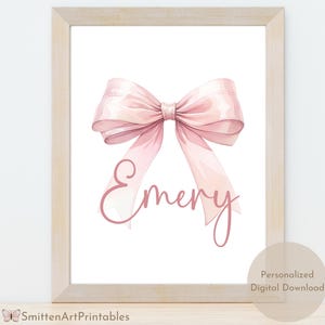 Puede incluir: Una descarga digital imprimible con un lazo rosa acuarela con el nombre "Emery" escrito en letra rosa.