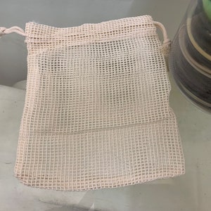 K&ouml;nnte beinhalten: Eine wei&szlig;e Netz-Zugschnur-Tasche mit einer wei&szlig;en Schnur. Die Tasche besteht aus einem feinen Netzmaterial und hat eine rechteckige Form.