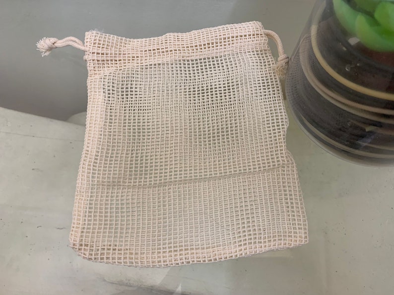 K&ouml;nnte beinhalten: Eine wei&szlig;e Netz-Zugschnur-Tasche mit einer wei&szlig;en Schnur. Die Tasche besteht aus einem feinen Netzmaterial und hat eine rechteckige Form.