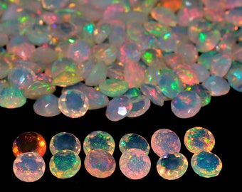 May include: A pile of iridescent white opal gemstones with a rainbow of colors.  The opals are round and have a smooth, polished finish.  There are also several opals in a row below the pile.