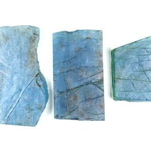 Puede incluir: Tres piezas de vidrio azul con un patrón de mármol. El vidrio es translúcido y tiene un color azul claro.