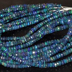 May include: A strand of blue opal beads, faceted and with a shimmery iridescent finish. The beads are strung on a white thread and are approximately 4mm in diameter.