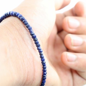 Könnte beinhalten: Ein blaues Edelstein-Armband aus kleinen, facettierten Perlen. Das Armband wird am Handgelenk getragen.